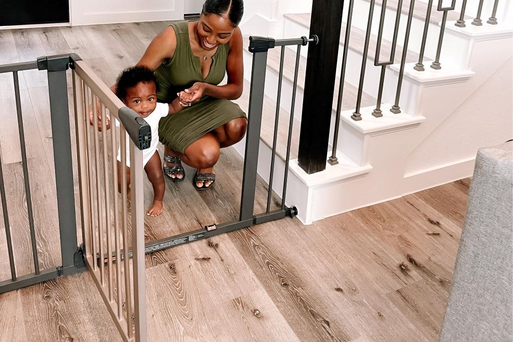 Parent testing baby gate durability by checking latch mechanism and mounting hardware