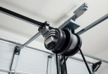 Homeowner safely testing garage door balance by lifting door to halfway position while wearing protective gloves and safety glasses