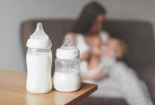 Assorted baby bottles suitable for breastfed babies, displayed on a nursery table