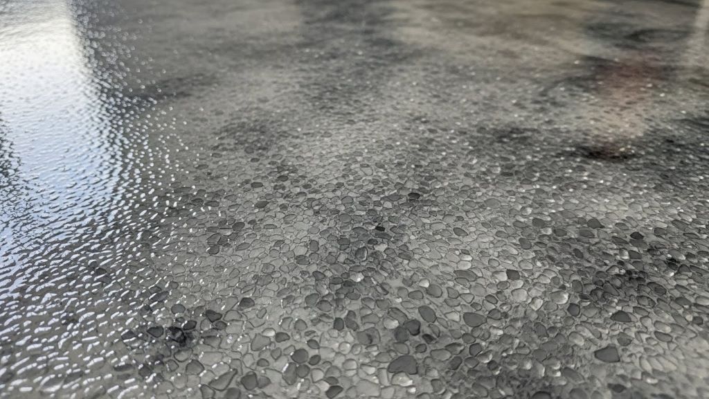 Close-up view of textured epoxy garage floor surface showing anti slip additive particles embedded in glossy finish