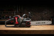 A premium cordless battery chainsaw placed on a wooden workbench in a workshop.