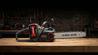 A premium cordless battery chainsaw placed on a wooden workbench in a workshop.