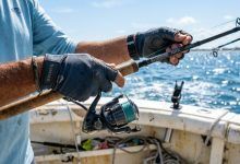 Angler wearing protective fishing gloves on a sunny Florida boat.