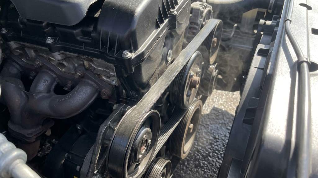 Automotive technician checking engine belt alignment
